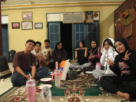 Anggota kelompok duduk santai bersama di ruang depan posko pada malam hari