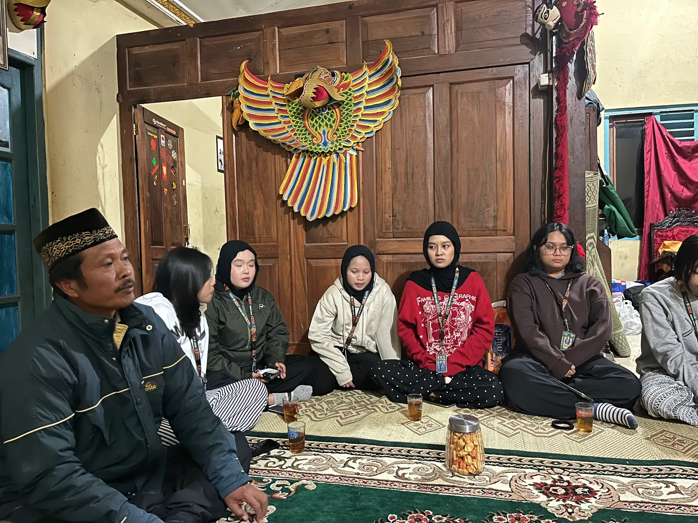 Mahasiswa dan warga duduk melingkar di ruang tamu untuk berbincang bersama