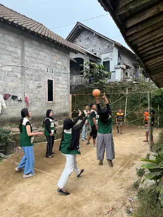 Mahasiswa dan warga bermain bola voli di lapangan kecil di antara rumah