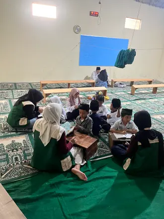 Mahasiswa mendampingi anak-anak membaca dan menulis dalam kelompok kecil di atas karpet