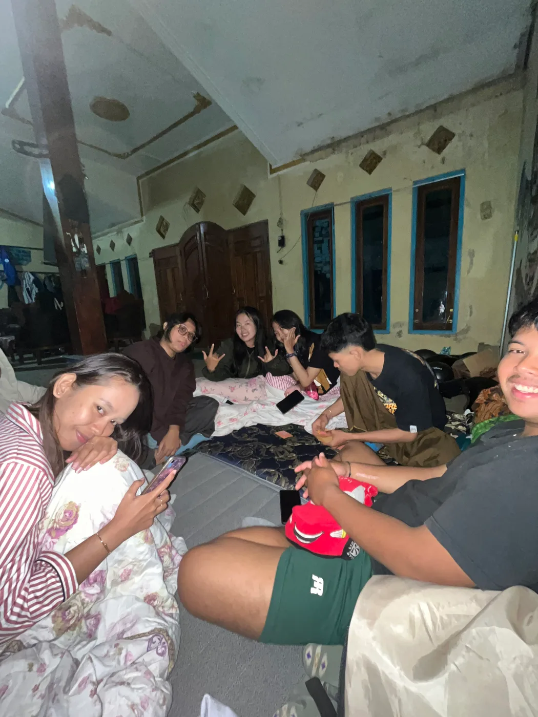 Anggota kelompok dan anak-anak duduk bersama di ruang posko pada malam hari