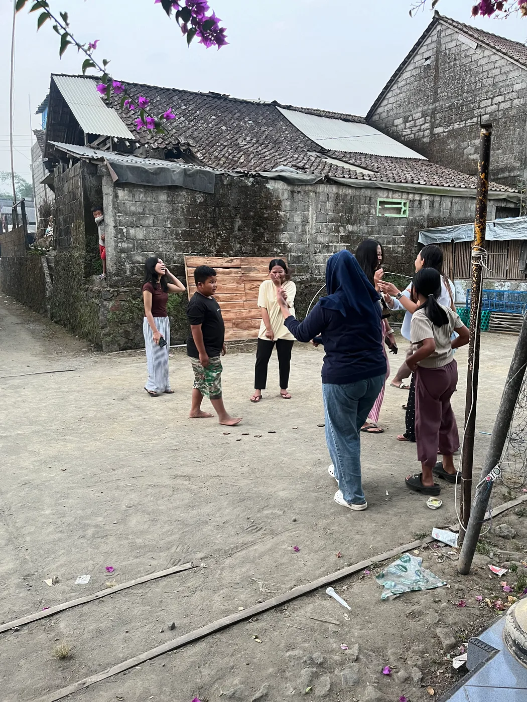 Mahasiswa berbincang dengan anak-anak yang berkumpul di halaman rumah warga