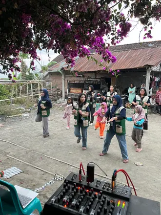 Mahasiswa memimpin latihan gerak bersama anak-anak di halaman dusun