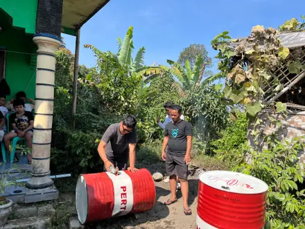 Tiga mahasiswa mengecat dan merakit drum merah putih menjadi tempat sampah