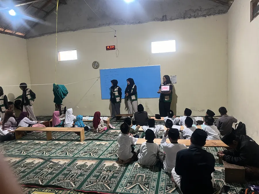 Mahasiswa menyampaikan materi di depan anak-anak yang duduk rapi dalam ruangan