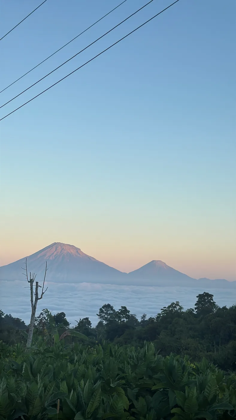 Dua gunung tampak berlapis di bawah langit pagi yang berwarna biru muda