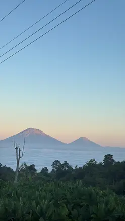 Dua gunung tampak berlapis di bawah langit pagi yang berwarna biru muda