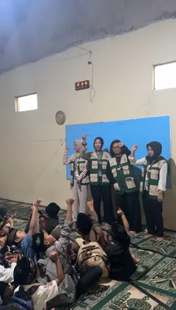 Empat mahasiswa berdiri di depan ruangan saat menyampaikan materi kepada anak-anak
