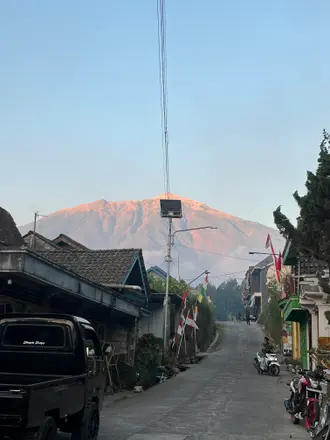 Gunung berwarna jingga terlihat dari jalan di antara rumah-rumah Sekendi