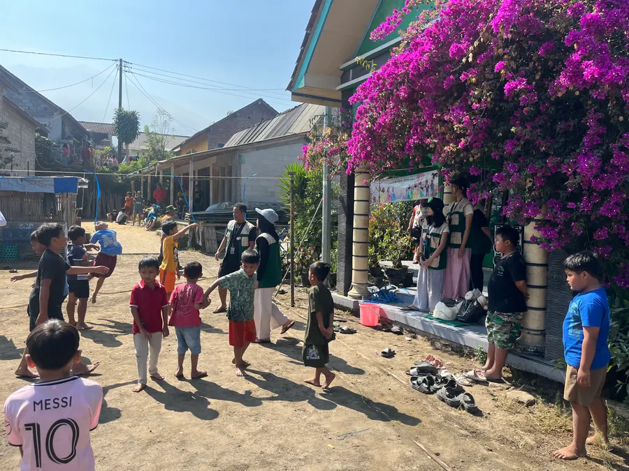 Anak-anak dan warga bermain bersama di lapangan dusun dekat bunga bugenvil